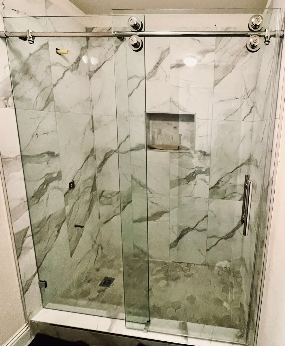 Frameless sliding shower door on marble tile